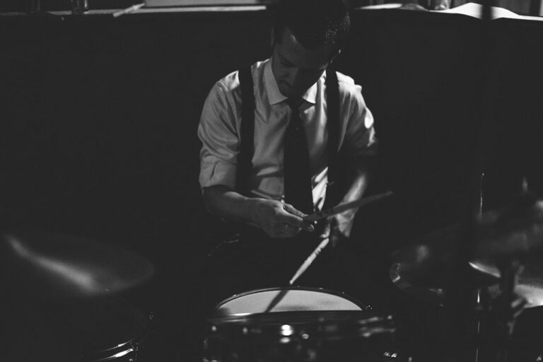 A man plays the drums in a dimly lit recording studio.