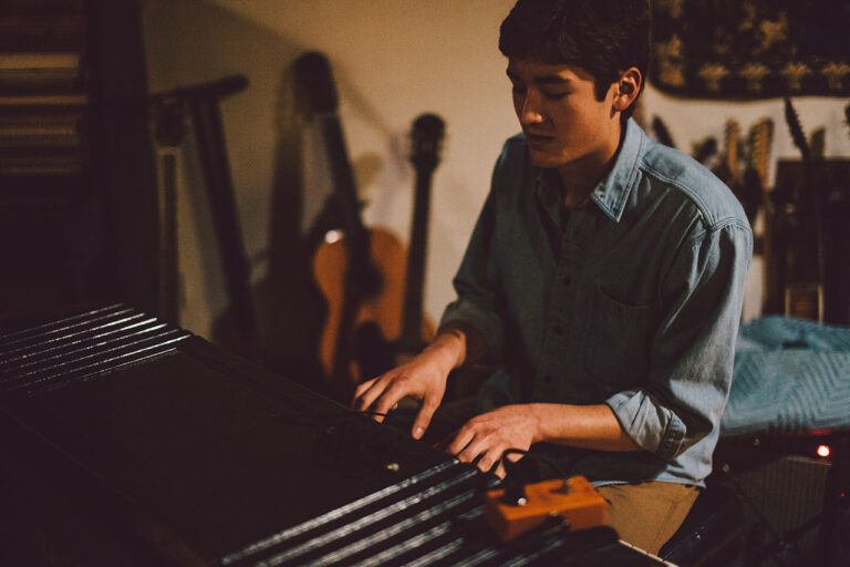 A man plays keyboard in a dimly lit recording studio.